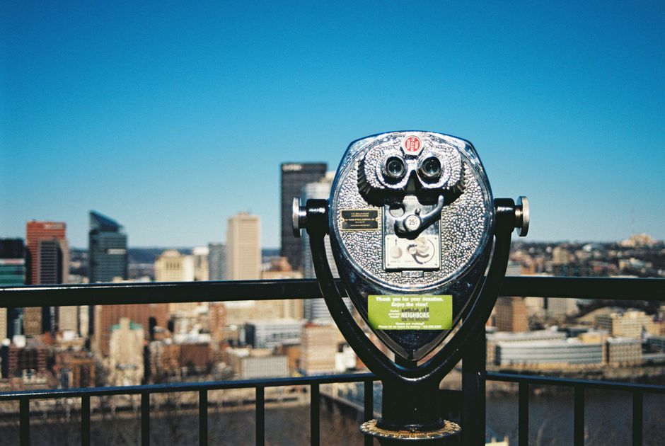 Coin-operated telescope with Pittsburgh skyline in background, stunning urban view.